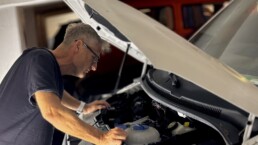 man looking under the hood of a car